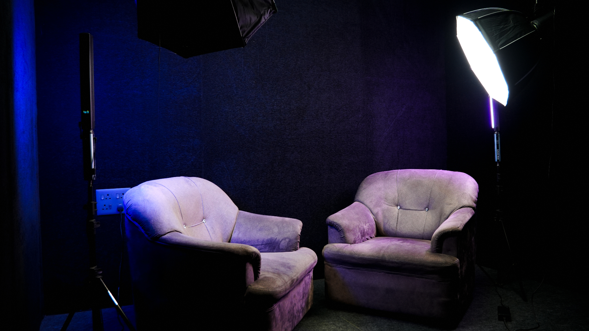 Podcast corner framed from the left side with two armchairs and studio lights