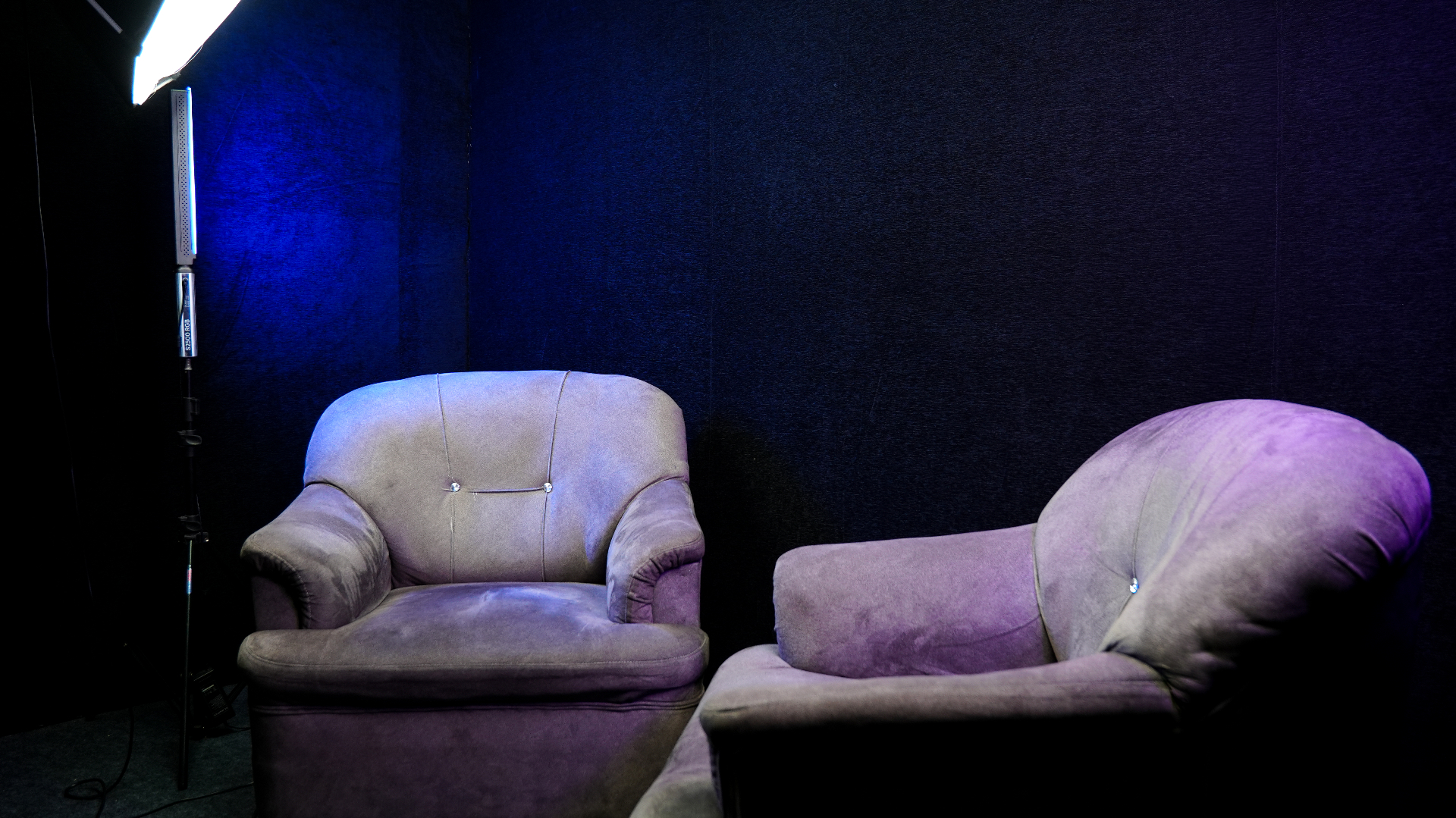 Podcast corner framed from the right side with two armchairs and studio lights